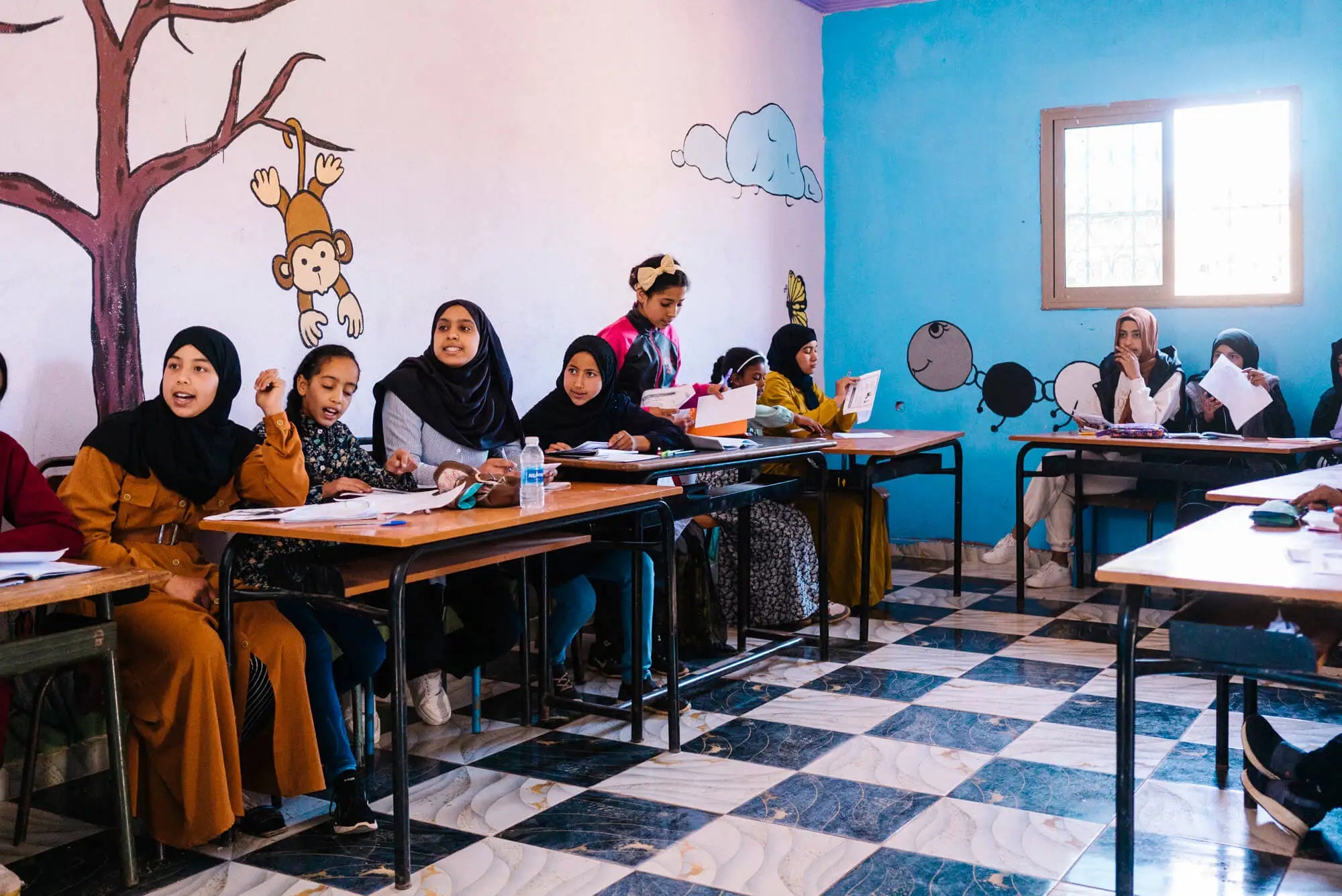Teenager-Mädchen aus Marokko sitzen in einem Klassenzimmer.