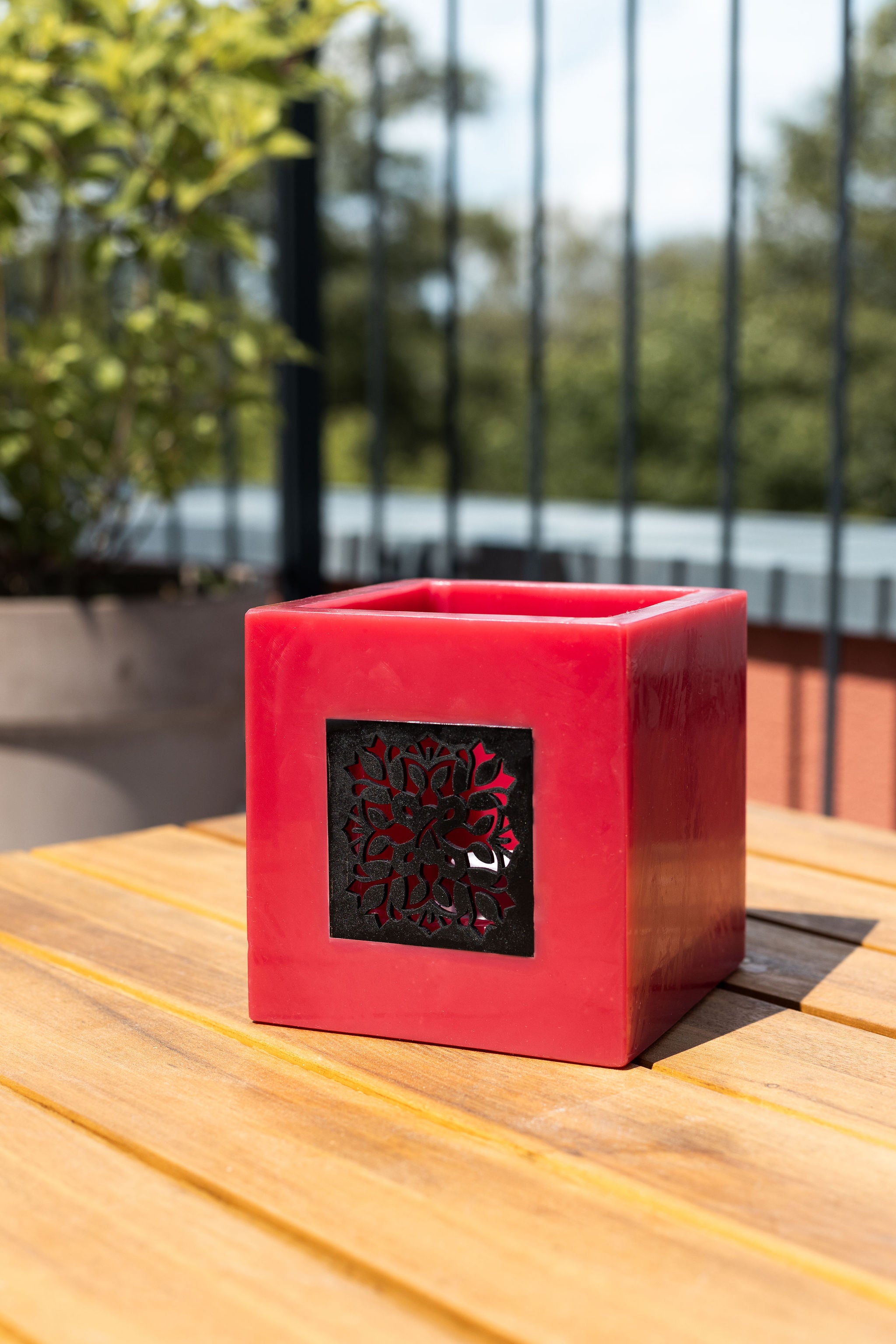 Rotes Windlicht aus Wachs mit Holzfenster auf einem Tisch. #farbe_rot