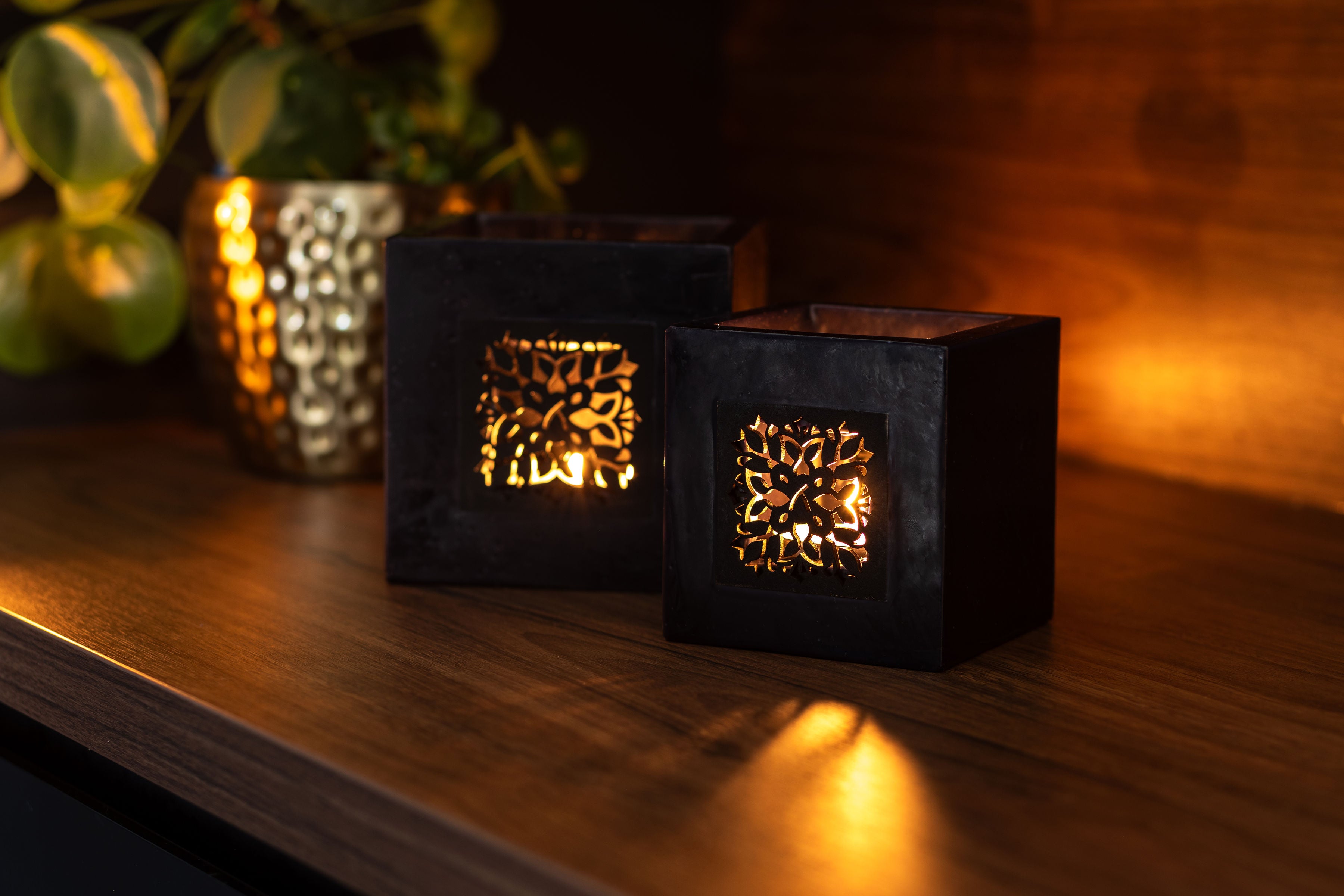 Zwei schwarze Windlichter auf einem Holzregal.