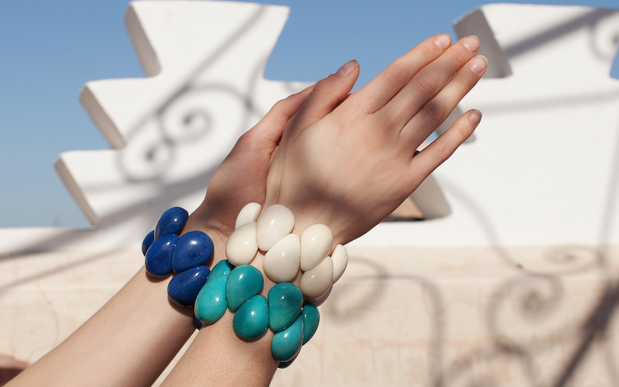 Tagua Armbänder in verschiedenen Farben an weiblichen Händen.