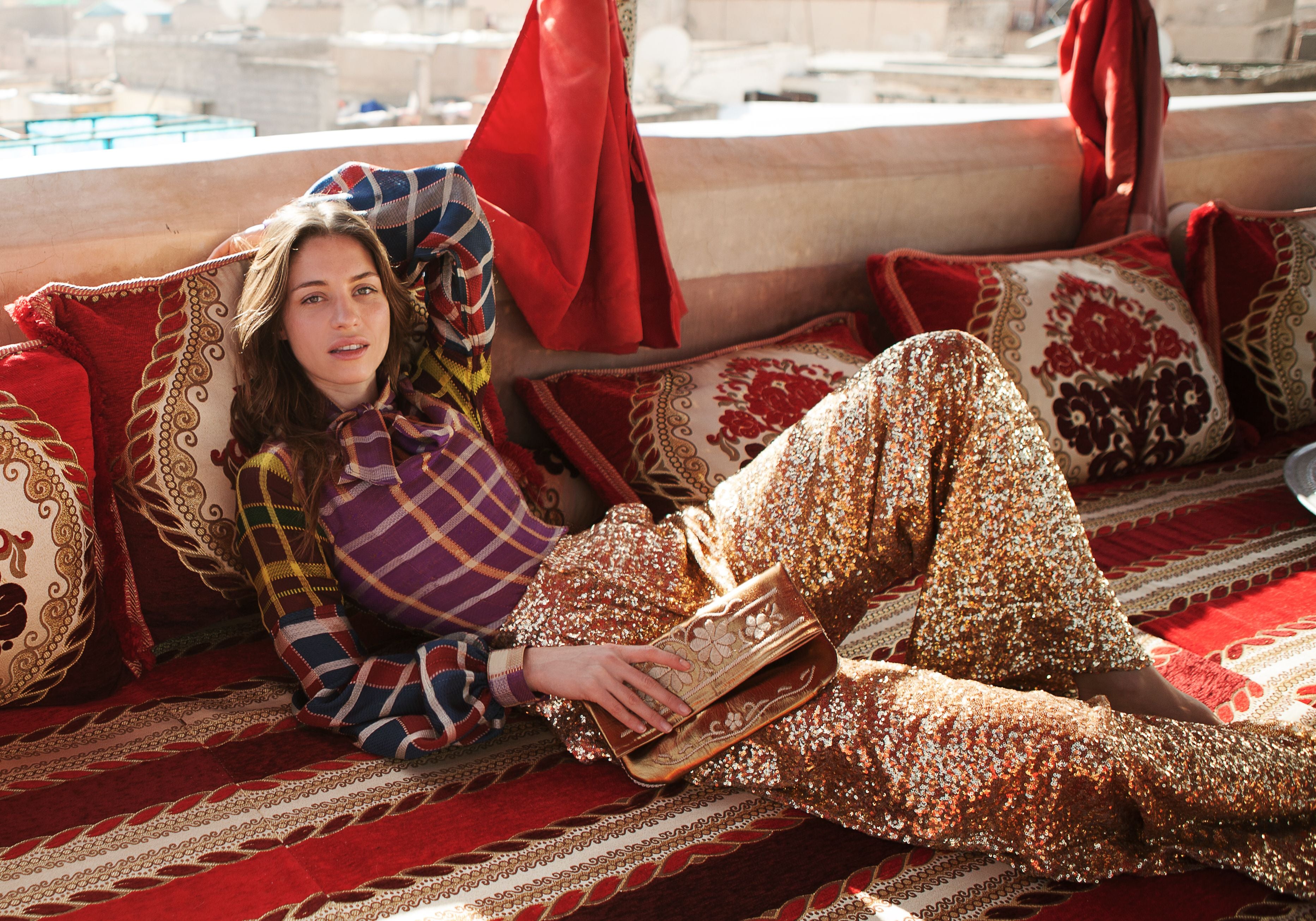 Frau mit ABURY Flower Power Clutch auf einem Sofa mit orientalischen Motiven