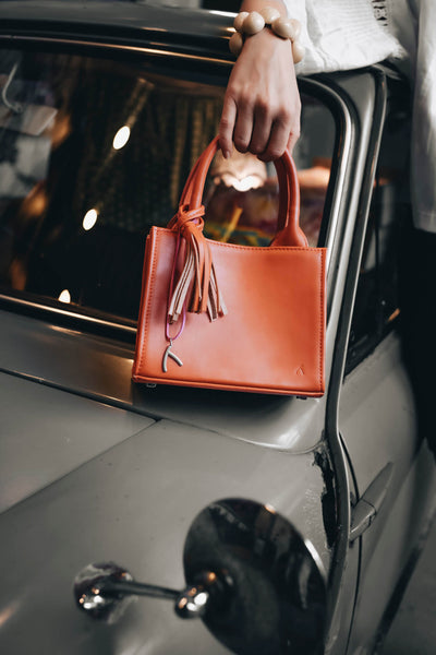 Frau posiert vor einem alten Trabant mit ihrer orangenfarbenen Mini-Tote-Bag. #farbe_orange