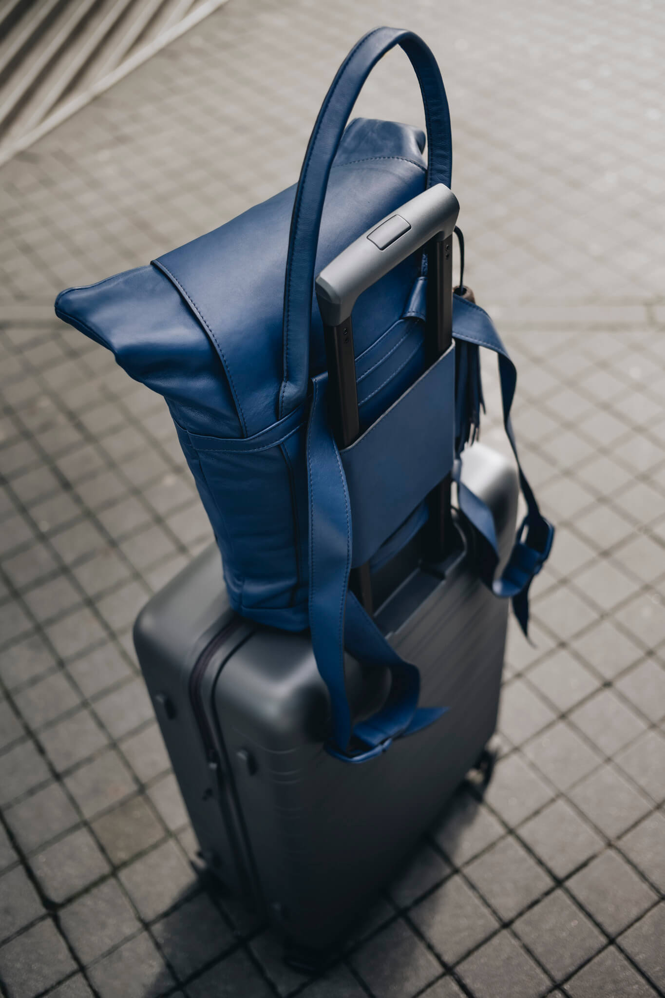 Ein blauer ABURY-Rucksack auf einem grauen Koffer. #farbe_blau