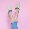 feet model in front of a pink background wearing jeans and abury beige raffia summer slippers with fringes
